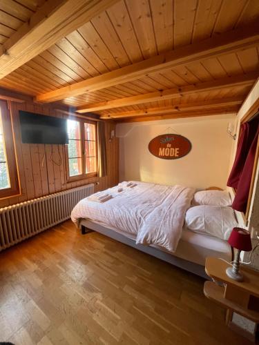 a large bed in a room with a wooden ceiling at L'Auberge de la Combal in La Comballaz