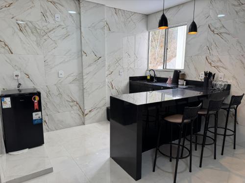 una cucina con un bar con sgabelli e pareti in marmo di Apartamento Central Próximo da praça Tiradentes e Hospital a Teófilo Otoni