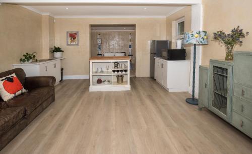 ein Wohnzimmer mit einem braunen Sofa und einer Küche in der Unterkunft LIMA HOUSE, Seaforth, Simon's Town in Simonʼs Town