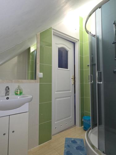 un bagno con lavandino, doccia e porta di Biesiadny Dworek a Szpegawa