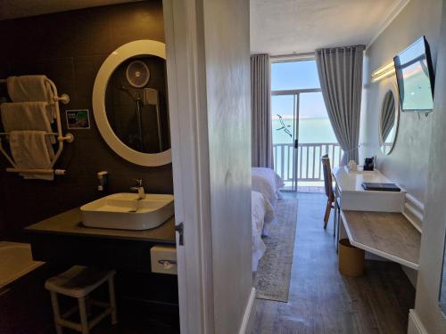 a bathroom with a sink and a bed and a mirror at Lüderitz Nest Hotel in Lüderitz