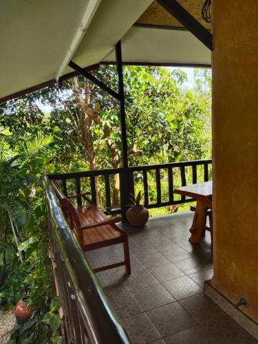a porch with a wooden bench and a table at Earth House HomeStay Bangjo in Ban Pak Lak