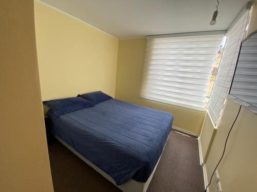 een slaapkamer met een blauw bed en een raam bij Viña Oriente in Viña del Mar