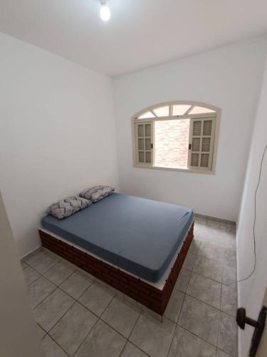 a bedroom with a bed in a room with a window at Casa Duque Peruíbe in Peruíbe