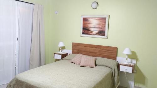 - une chambre avec un lit, deux lampes et une photo dans l'établissement Apartamento Confortable Samai Huasi, à Las Grutas