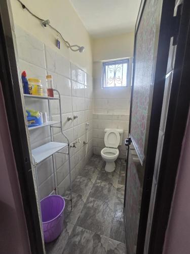 a small bathroom with a toilet and a window at Flynn Stays in Bamburi