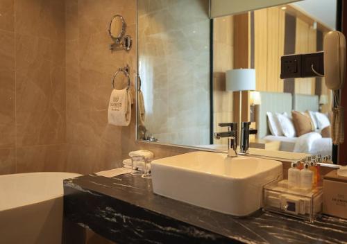 un bagno con un lavandino, uno specchio e una vasca di Atlantiis Suites Inn Mahmoorganj Near Vishwanath Temple a Varanasi