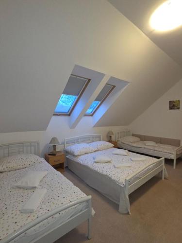 three beds in a room with three windows at Biesiadny Dworek in Szpegawa