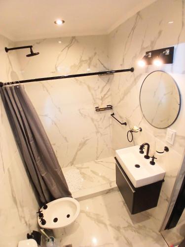 a white bathroom with a sink and a mirror at Departamentos Necochea Playa in Necochea
