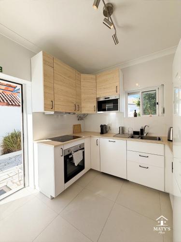 a kitchen with white cabinets and a large window at Maty's Place in Mafra
