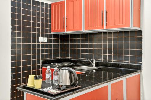 een keuken met zwarte betegelde muren en rode kasten bij Al Thill Hotel in Mekka