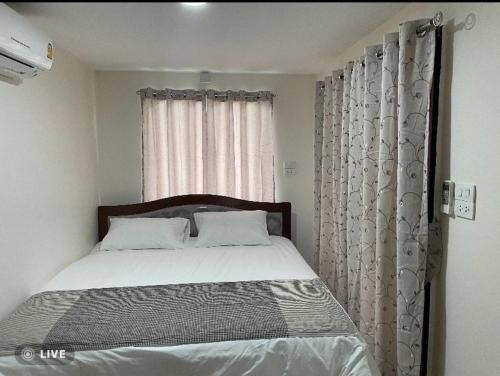 een slaapkamer met een bed en een raam met gordijnen bij Mae on country home in Ban On Luai