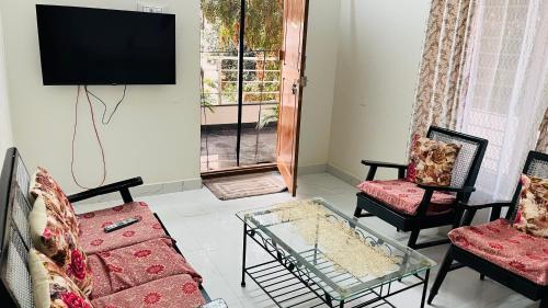 a living room with two couches and a tv at Boutique Bungalow 458 in Secunderabad