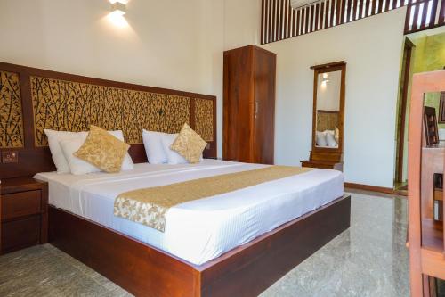 une chambre avec un grand lit avec une tête de lit en bois dans l'établissement Grand Ranketha Resort, à Kalutara