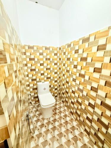 a bathroom with a toilet in a tiled wall at Hotel embrace in Bhauli