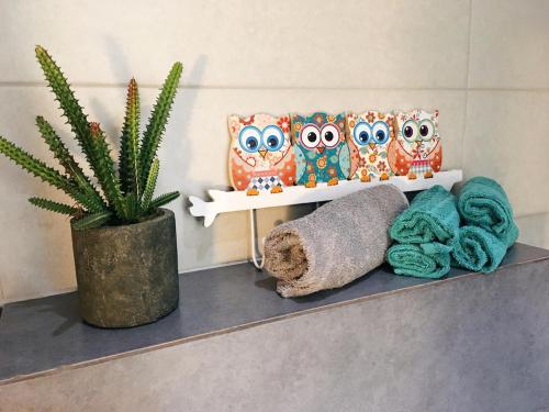 a shelf with owls on it with towels and a plant at Lucas Apart 2Bdr & 2Bth with pool in Mār Yūsuf