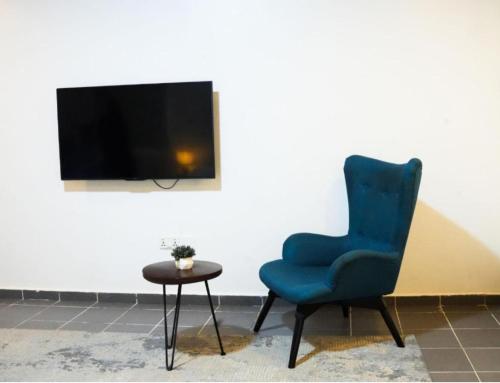 een blauwe stoel en een tafel in een kamer bij Homecoming Maitama in Abuja
