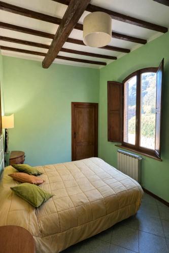 a bedroom with a bed with green walls and a window at Vita Toscana Guest House in Chiusi
