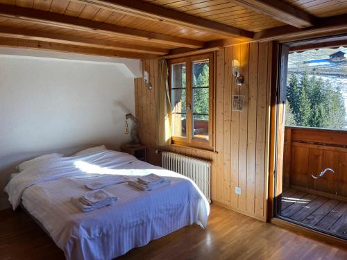 una camera da letto con un letto in una stanza con una finestra di L'Auberge de la Combal a La Comballaz