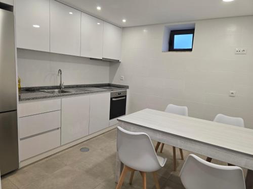 una cucina con mobili bianchi, tavolo e sedie di Uíma River House 