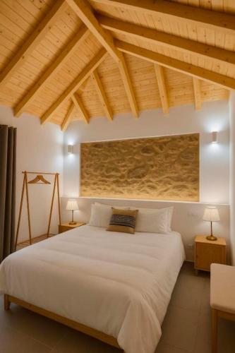 a bedroom with a large white bed and wooden ceilings at Uíma River House in Lobão