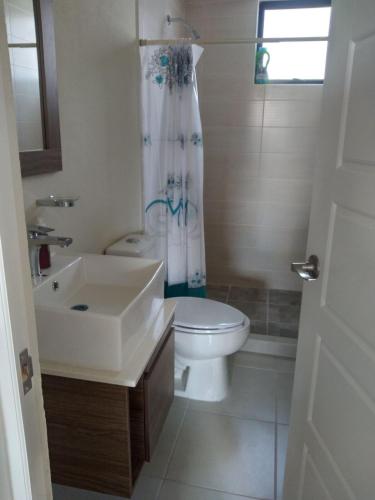 a white bathroom with a sink and a toilet at House B Residential condominium with pool in Miranda