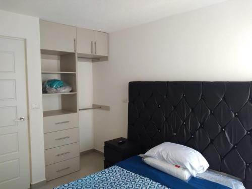 ein Bett mit einem schwarzen Kopfteil in einem Schlafzimmer in der Unterkunft House B Residential condominium with pool in Miranda