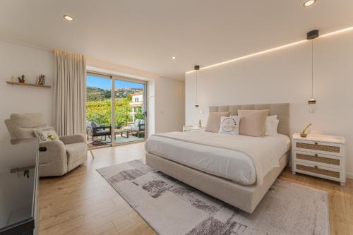 a bedroom with a large white bed and a chair at The Viewpoint by Eurostay in Ribeira Brava