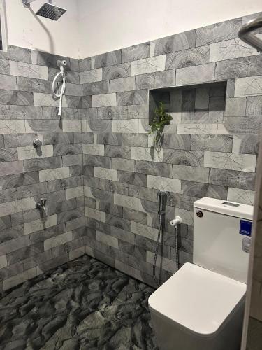 a bathroom with a toilet and a stone wall at AURORA Midigama in Ahangama