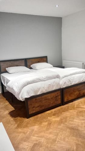 a bedroom with two beds with white sheets and wooden floors at Number 5 in Harwich