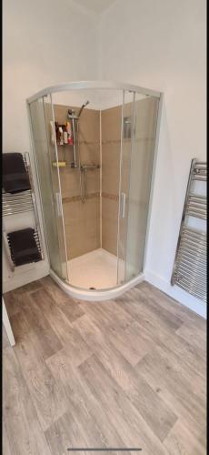 a glass shower in a room with a wooden floor at The Victorian Terrace in Morecambe