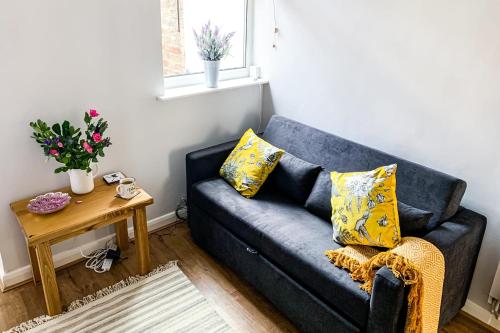 a blue couch with yellow pillows in a living room at The Knavesmire - Quaint Victorian Home - Free Parking - Pet Friendly in York