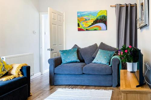 a blue couch in a living room with a painting at The Knavesmire - Quaint Victorian Home - Free Parking - Pet Friendly in York