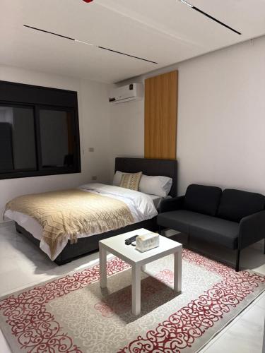 ein Schlafzimmer mit einem Bett, einer Couch und einem Tisch in der Unterkunft Riva suites in Irbid