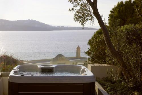 una vasca da bagno piena d'acqua accanto a uno specchio d'acqua di Hotel Adonis a Mykonos Città