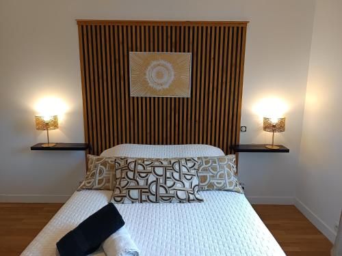 een slaapkamer met een bed met twee lampen aan de muur bij Hébergement quartier historique in Parthenay