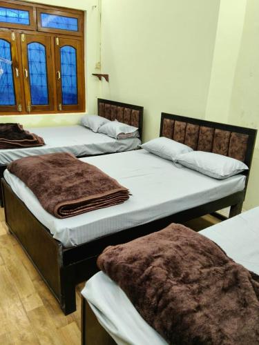 a group of three beds in a room at Tridev Hills in Ujjain