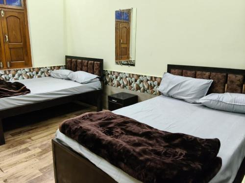 a room with two beds and two windows at Tridev Hills in Ujjain