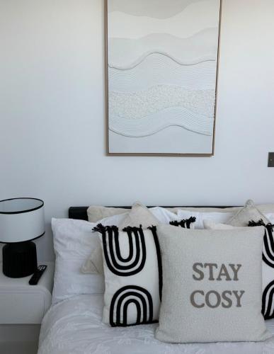 a white bed with black and white pillows and a picture at Cosy flat that feels just like home in Leavesden Green