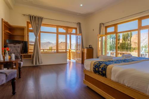 a bedroom with a large bed and a balcony at The Nangsay Hotel in Leh