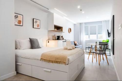 a white bedroom with a large bed and a table at Genesis-Loft San Enrique 14 in Madrid