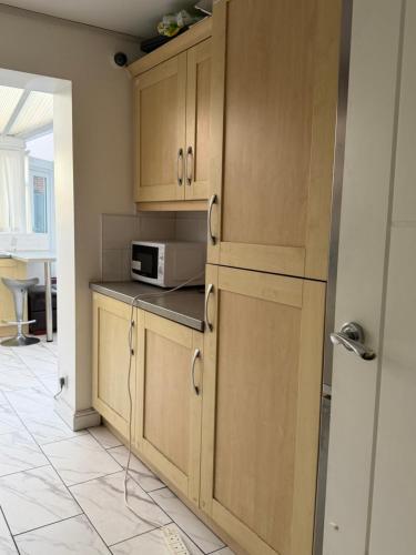 a kitchen with wooden cabinets and a microwave at Nightingale Roomz in Lower Darwen