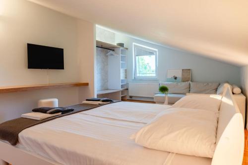 a large white bed in a room with a flat screen tv at Private Pool Villa with Garden & Nature by Destination GREEN Croatia in Pregrada