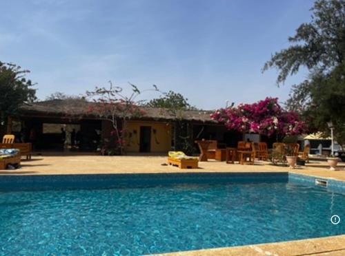 a swimming pool in front of a house at Kabacoto Lodges in Darou Rhamane