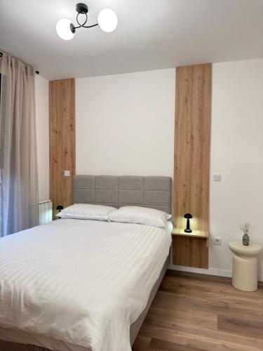 a bedroom with a large white bed and wooden floors at CENTRAL SQUARE Tuzla in Tuzla