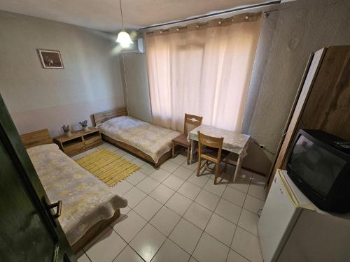 a room with two beds and a table and a tv at Villa Lira in Pavel Banya