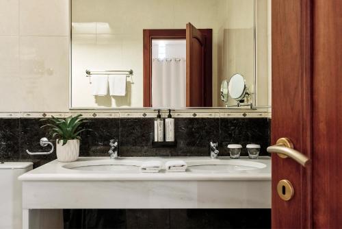 un bagno con due lavandini e un grande specchio di Hotel Adonis a Mykonos Città