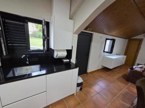 una cucina con mobili bianchi, un lavandino e una finestra di Quinta da Estacao a Marco de Canaveses