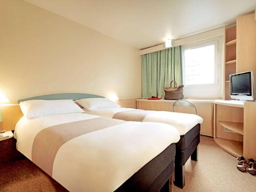 um quarto de hotel com duas camas e uma televisão em ibis Chambery em Chambéry