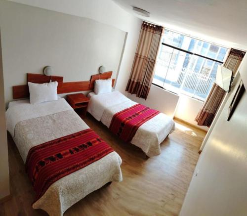 een slaapkamer met twee bedden en een groot raam bij Mi Hostal Cusco in Cuzco